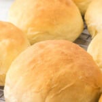 Closeup of hamburger buns on a wire rack with title text overlay for Pinterest.