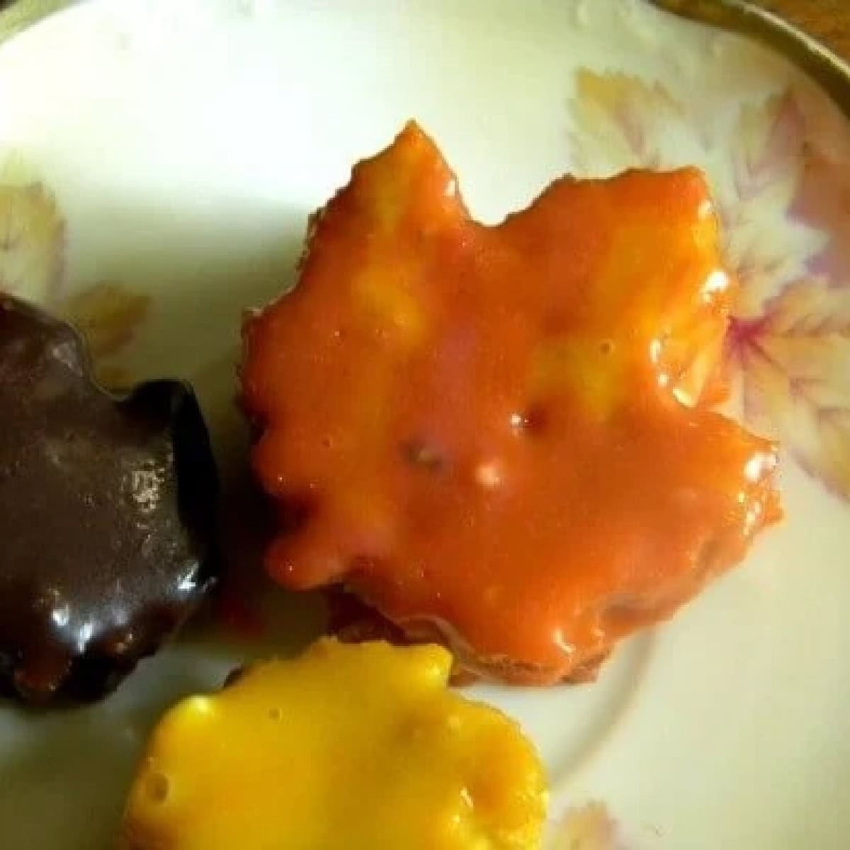 Closeup of the pumpkin petit fours cut to look like maple leaves and decorated  with orange, yellow, and brown glaze.