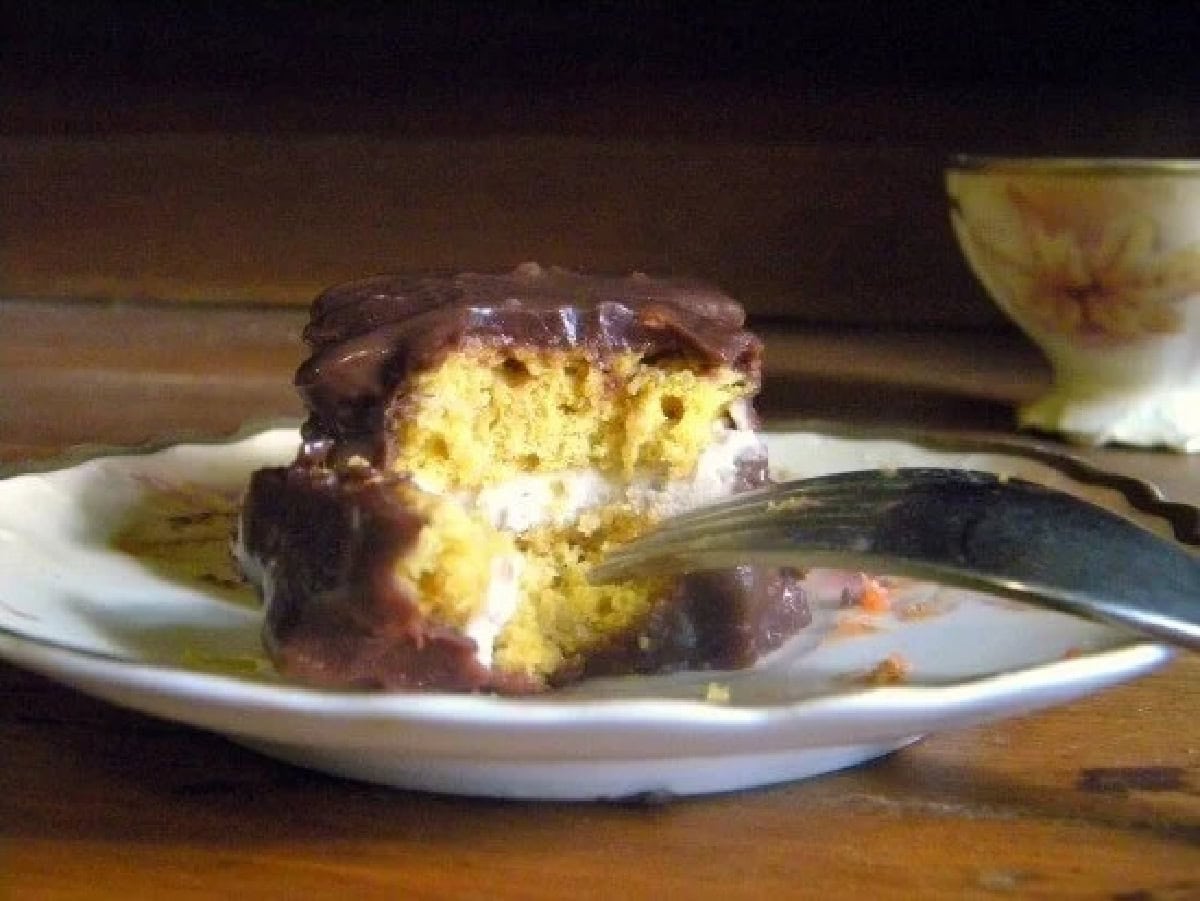 Closup of a pumpkin petit four with half removed to view the layers of cake and filling.