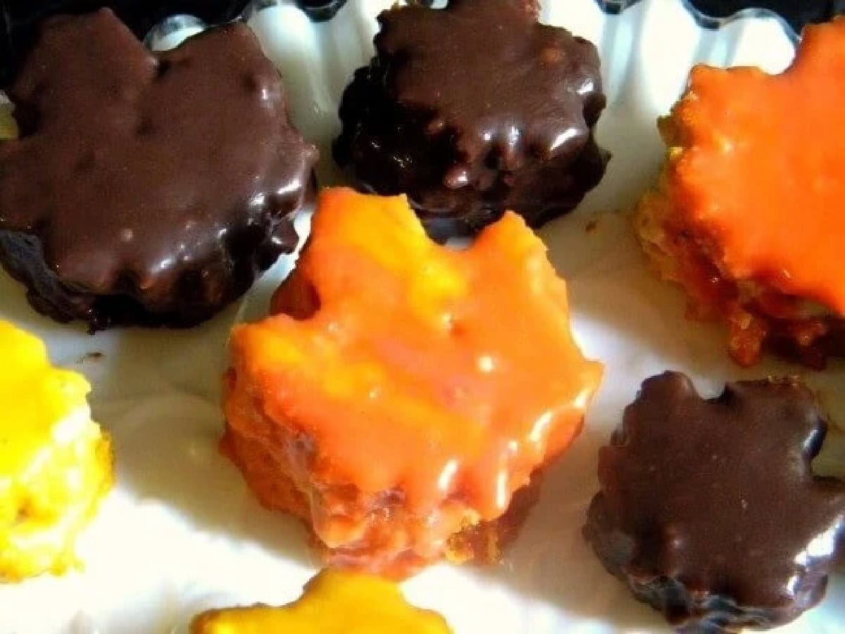 Overhead view of the pumpkin petit fours on a tray in a variety of different colors.