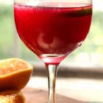 Red sangria in a balloon glass with text overlay for Pinterest.
