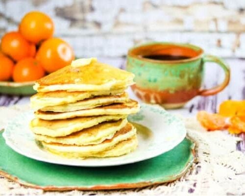 stack of buttermilk pancakes with oranges in the background.