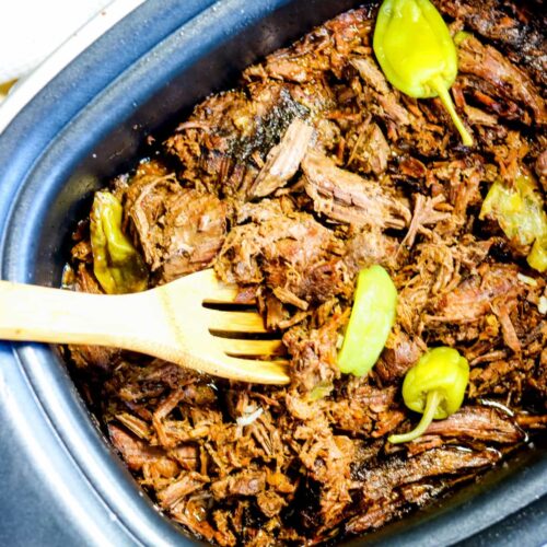 Close up of shredded pot roast meat in a slow cooker.