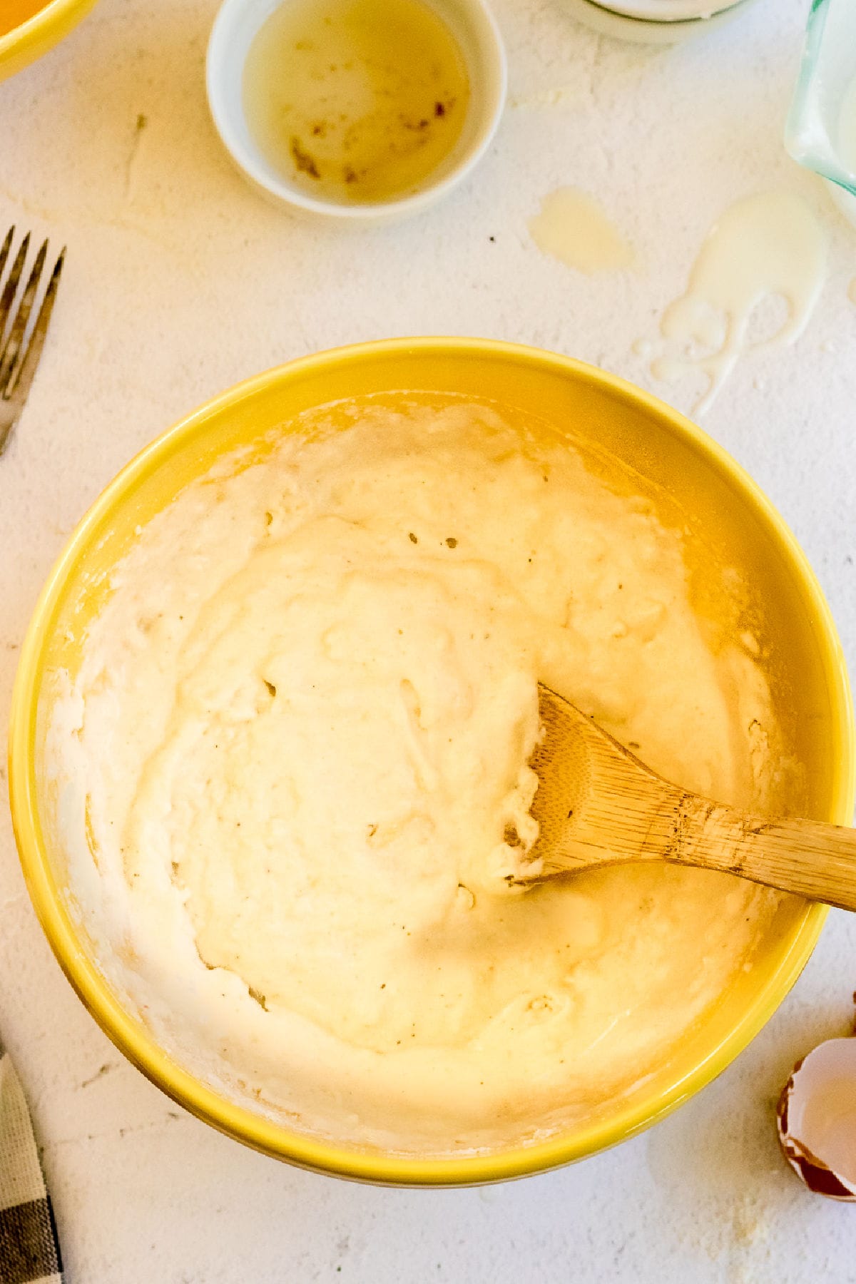 Wet and dry ingredients mixed in a yellow bowl to make a batter.