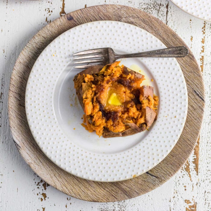 Overhead view of a baked sweet potato on a white plate.