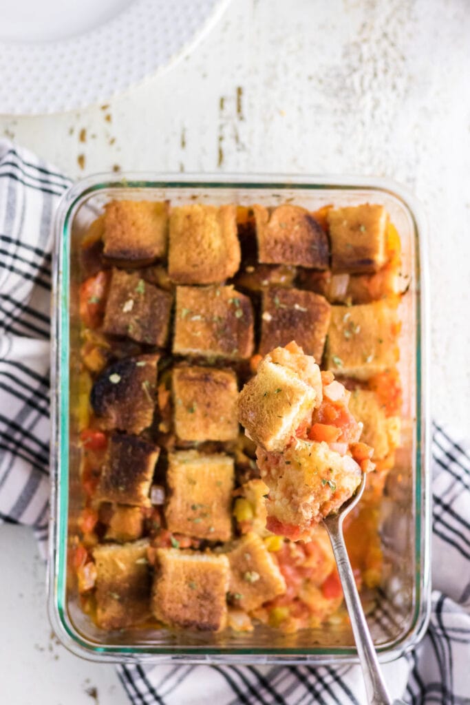 A serving of tomato casserole being removed from the baking dish.