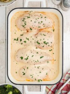 Overhead view of the chicken covered in gravy in a white casserole dish.