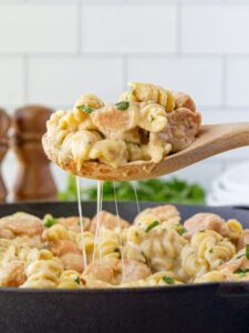 A serving of mac and cheese being spooned up from a pan.