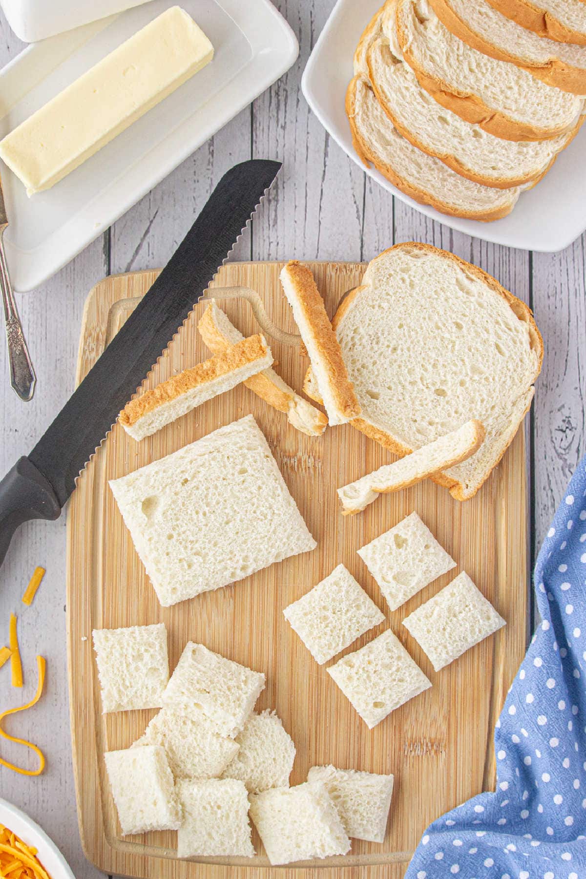 Bread with crusts removed being cut into small squares.