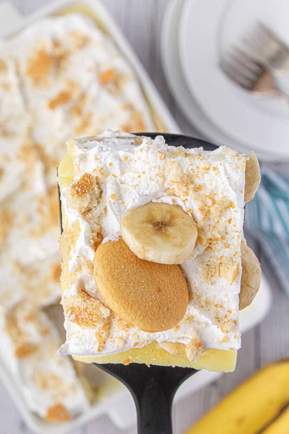 An overhead view of a slice of banana poke cake with whipped cream and sliced bananas.