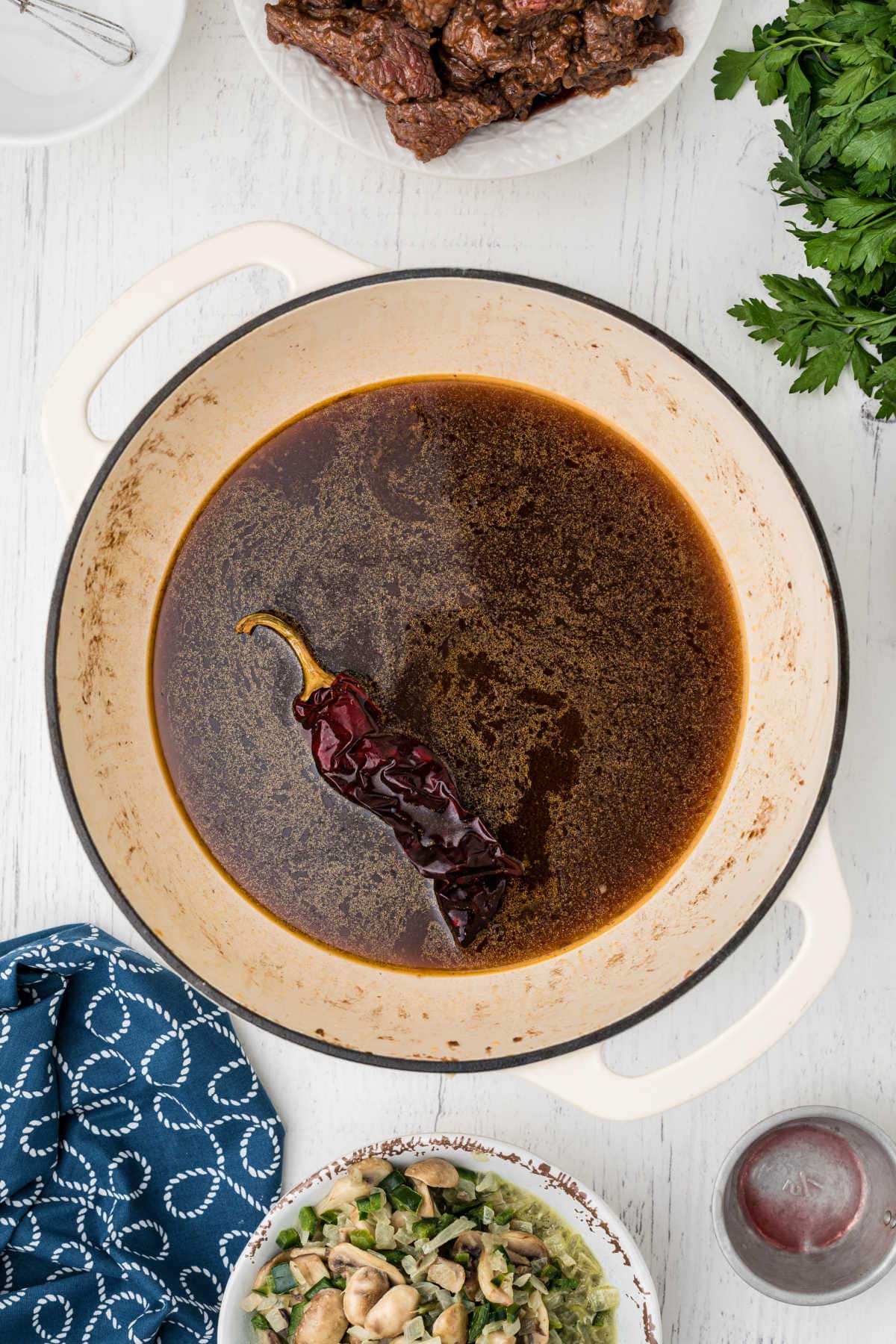 Beef stock mixture is simmering with a guijillo chile added to it.