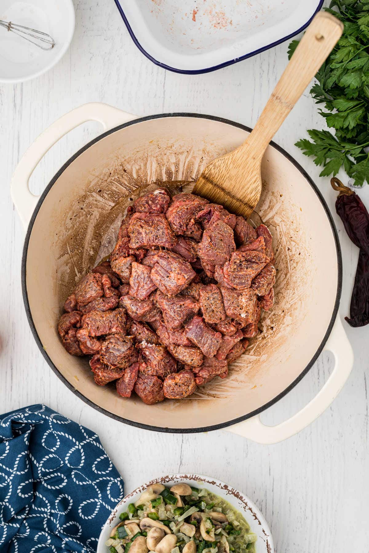 The seasoned beef is added to the dutch oven.