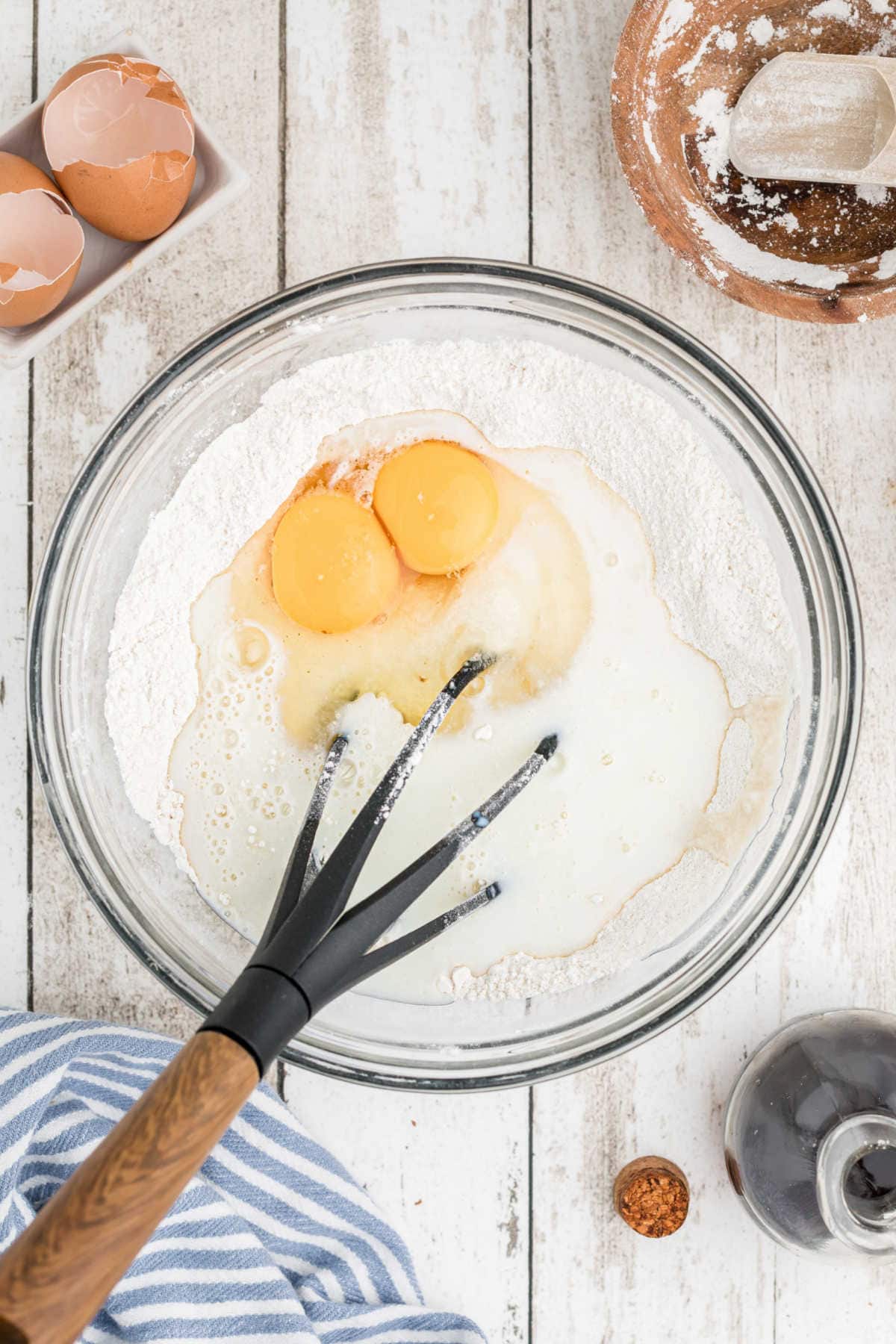 A bowl with flour, eggs, and buttermilk being whisked together.