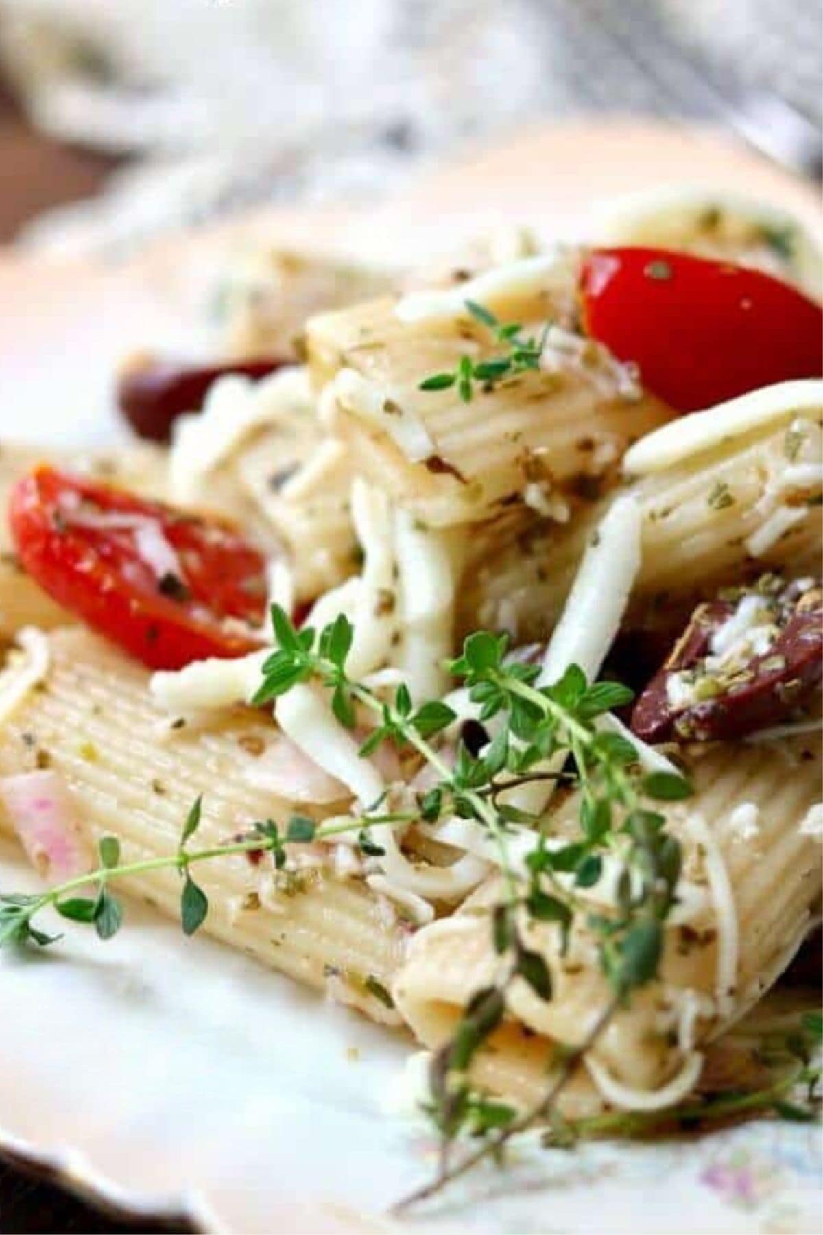 Closeup of pasta salad with fresh herbs, olives, and cherry tomatoes.