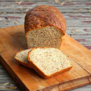 A loaf of cracked wheat bread on a cutting board.