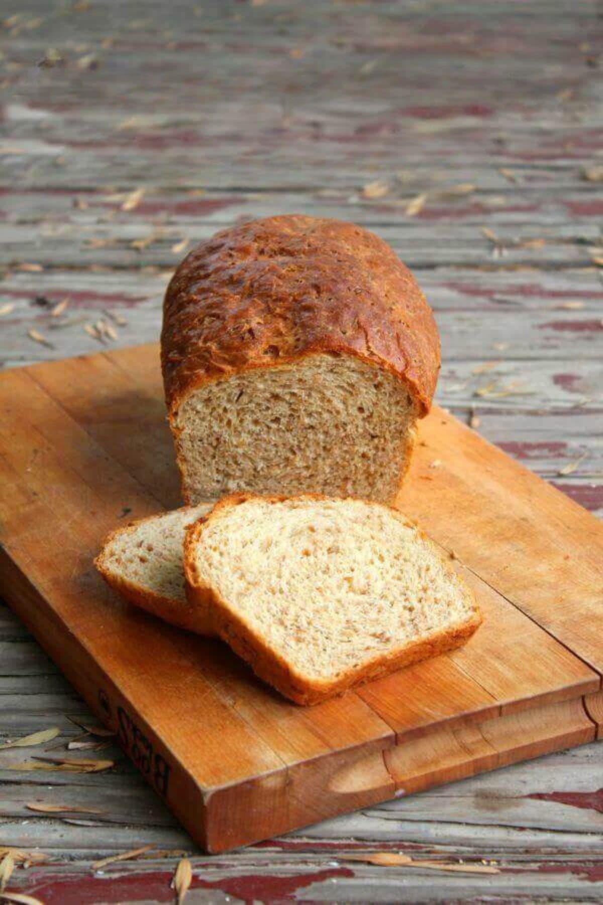 A loaf of buttermilk cracked wheat bread that has been sliced on a cutting board.