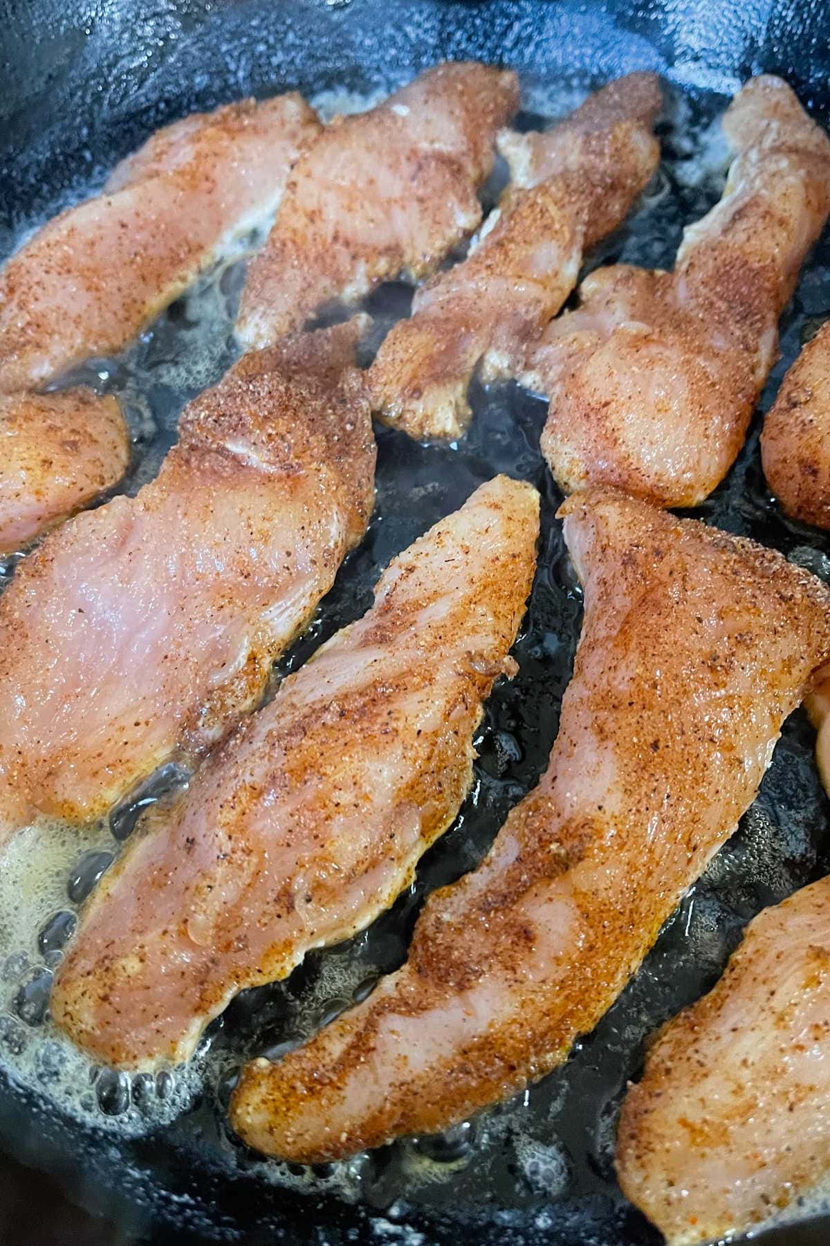Searing the chicken in a skillet.