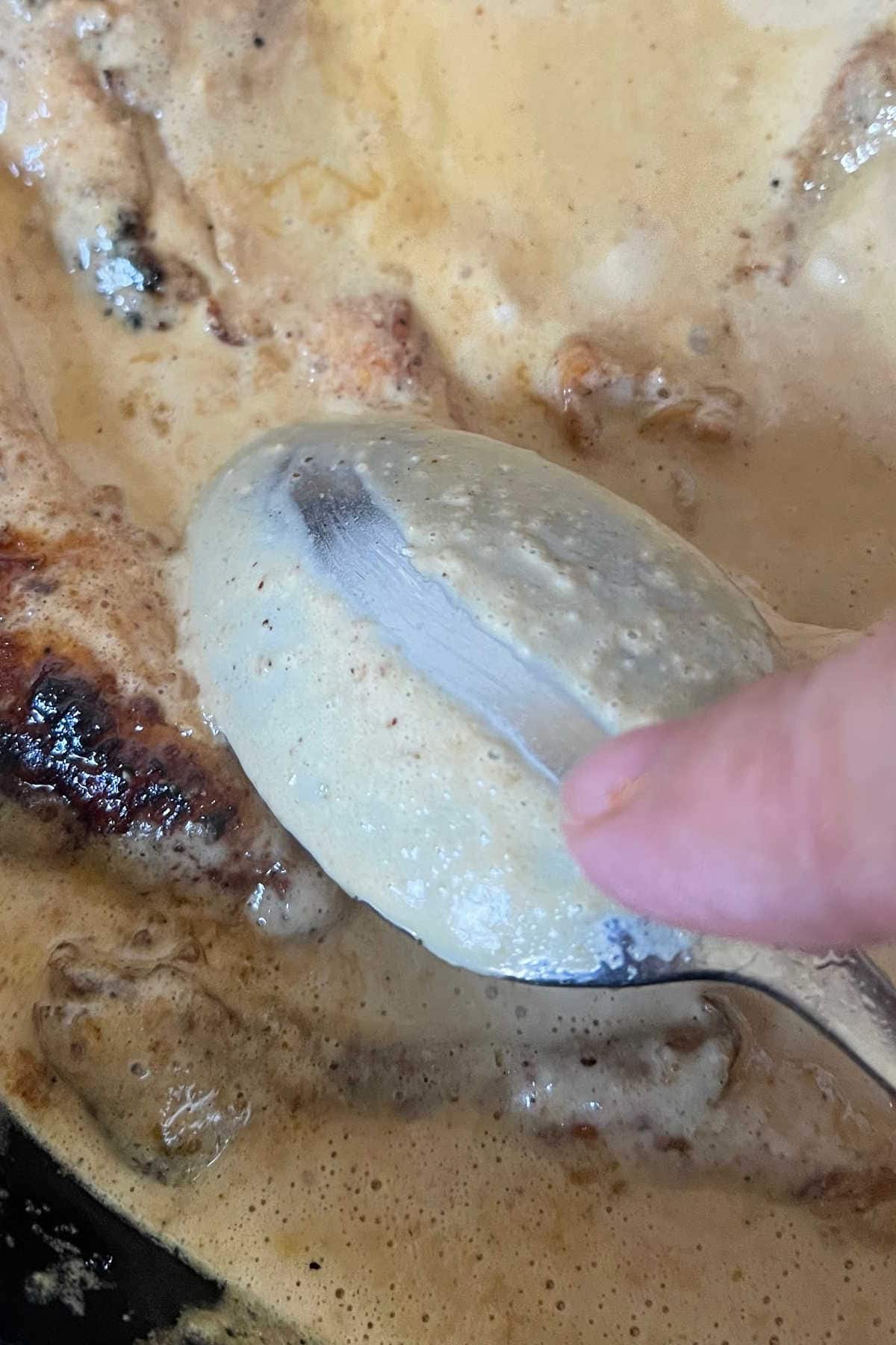 Testing the sauce for thickness on the back of a spoon.