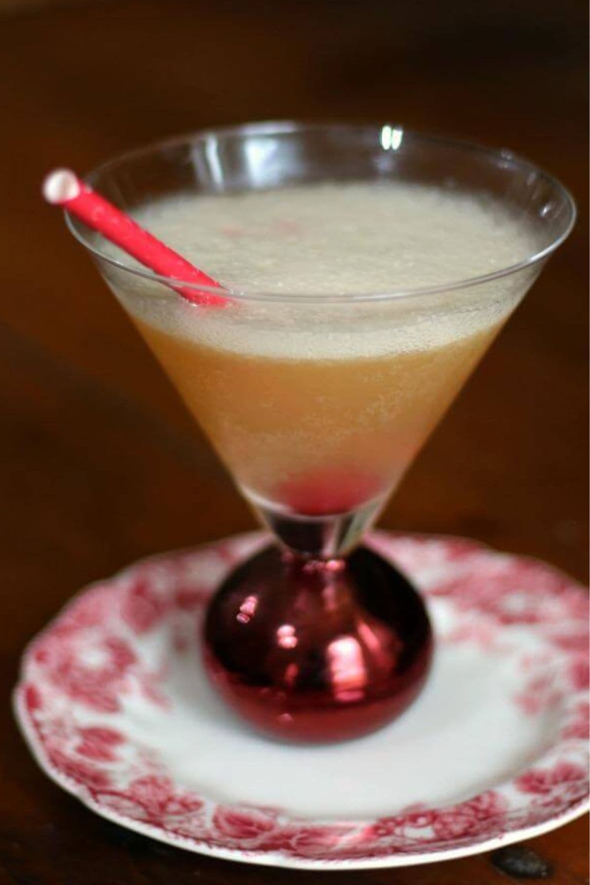 Closeup of the commodore cocktail in a martini glass with a red straw.