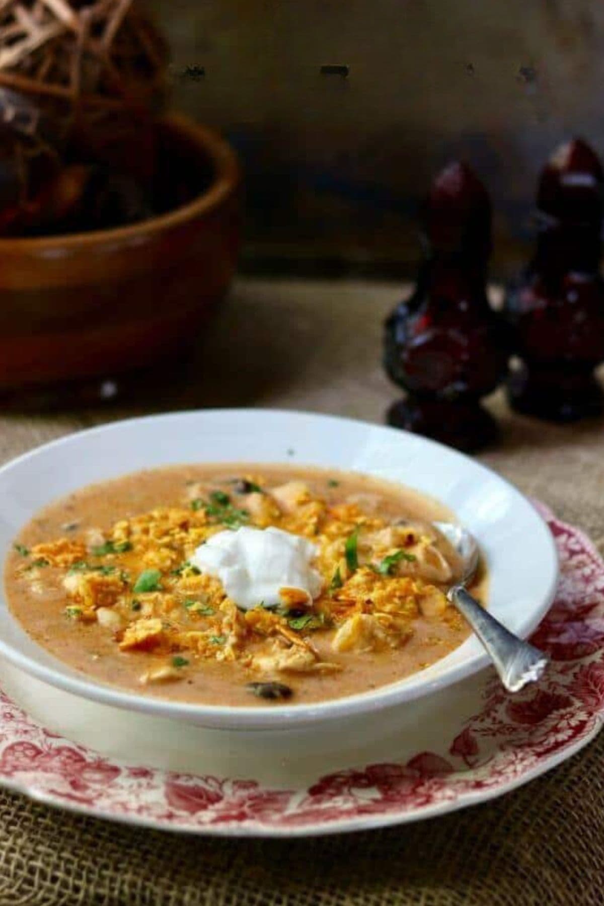 A bowl of chicken enchilada soup with a dollop of sour cream on top.