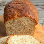 A loaf of cracked wheat bread on a cutting board with a title text overlay for Pinterest.