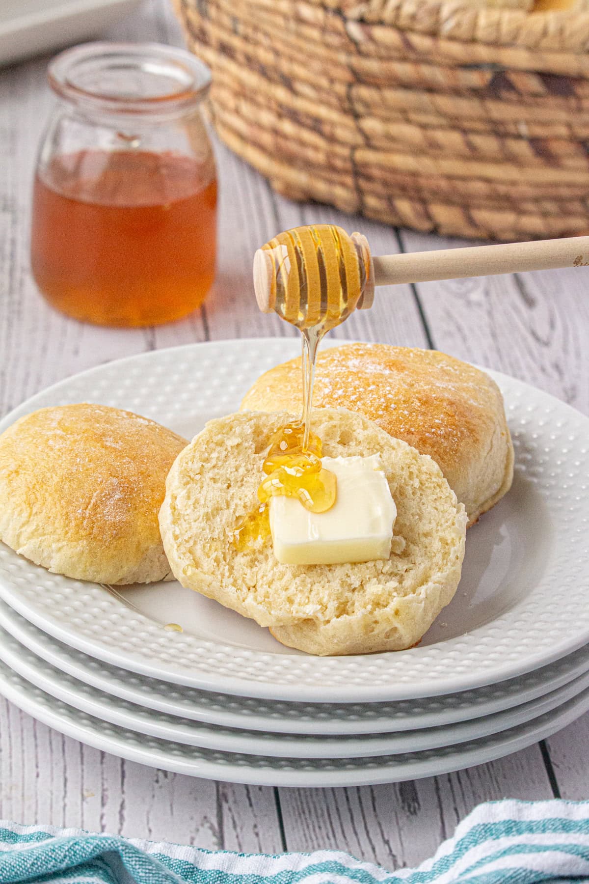 Hot dinner rolls on a plate with honey drizzled on them.