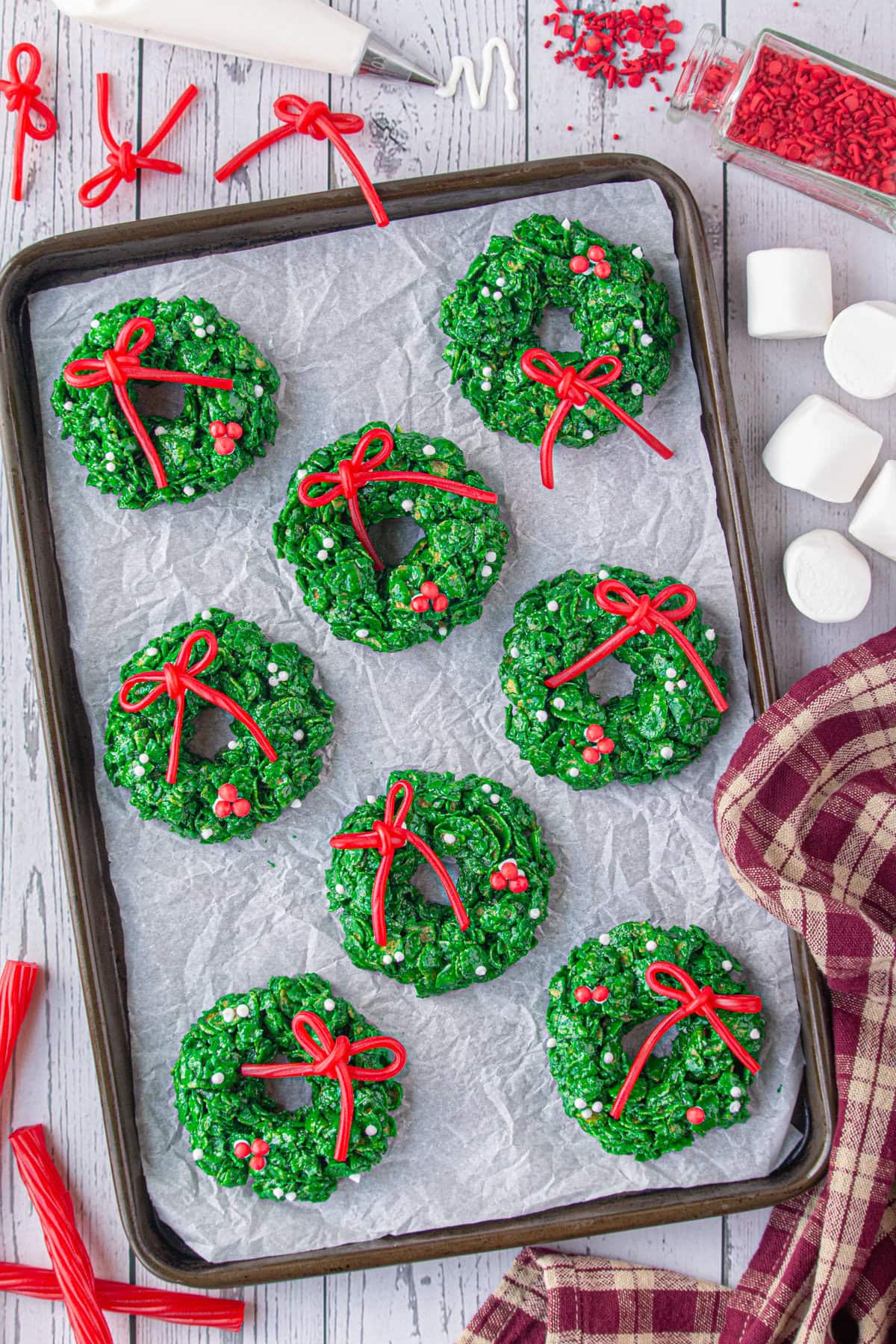 Cornflake Christmas wreath cookies formed and decorated on a cookie sheet.