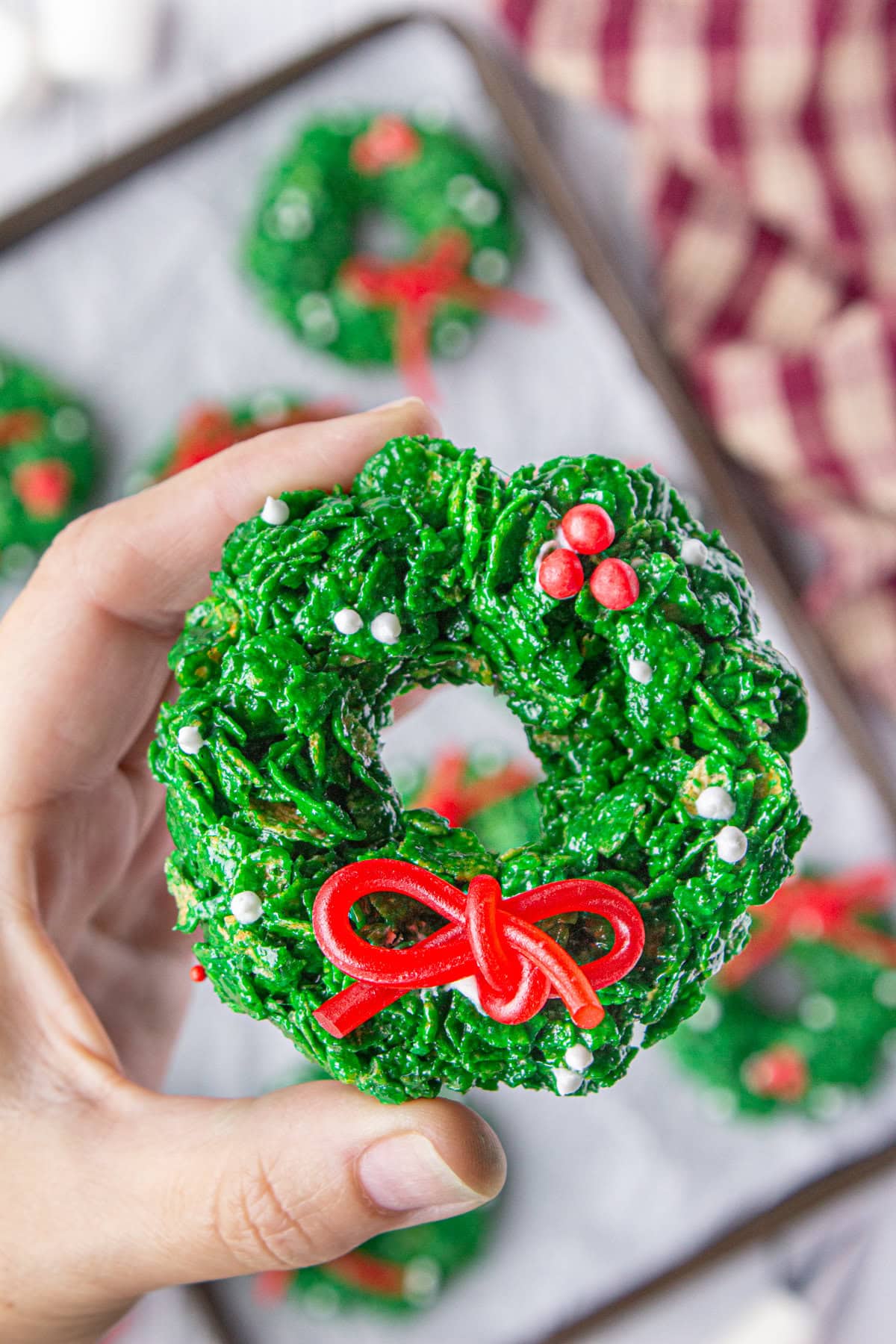 A close-up view of a cornflake Christmas wreath cookie with sprinkles and a bow.