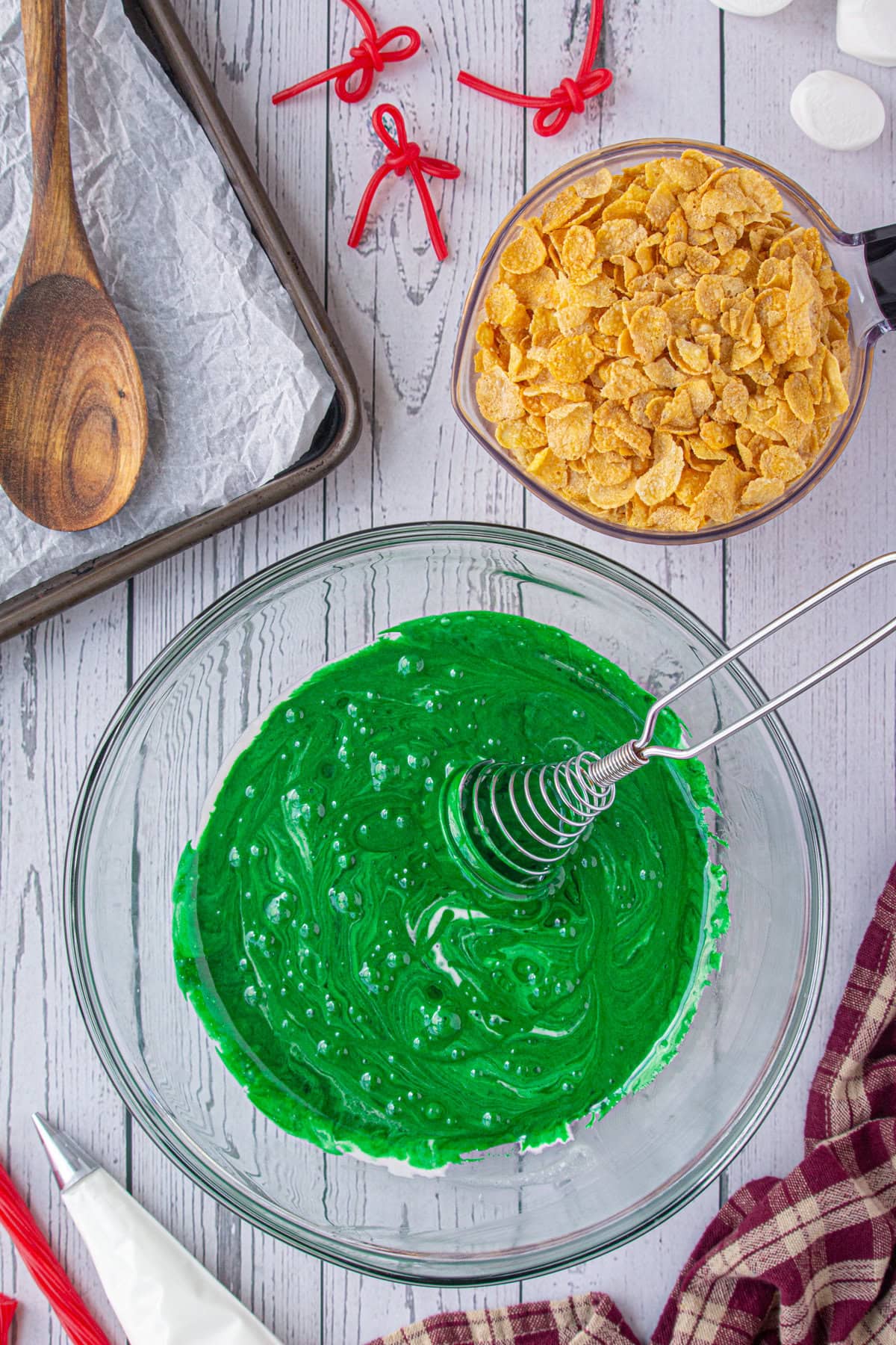 Adding green food coloring to the melted marshmallow mixture.