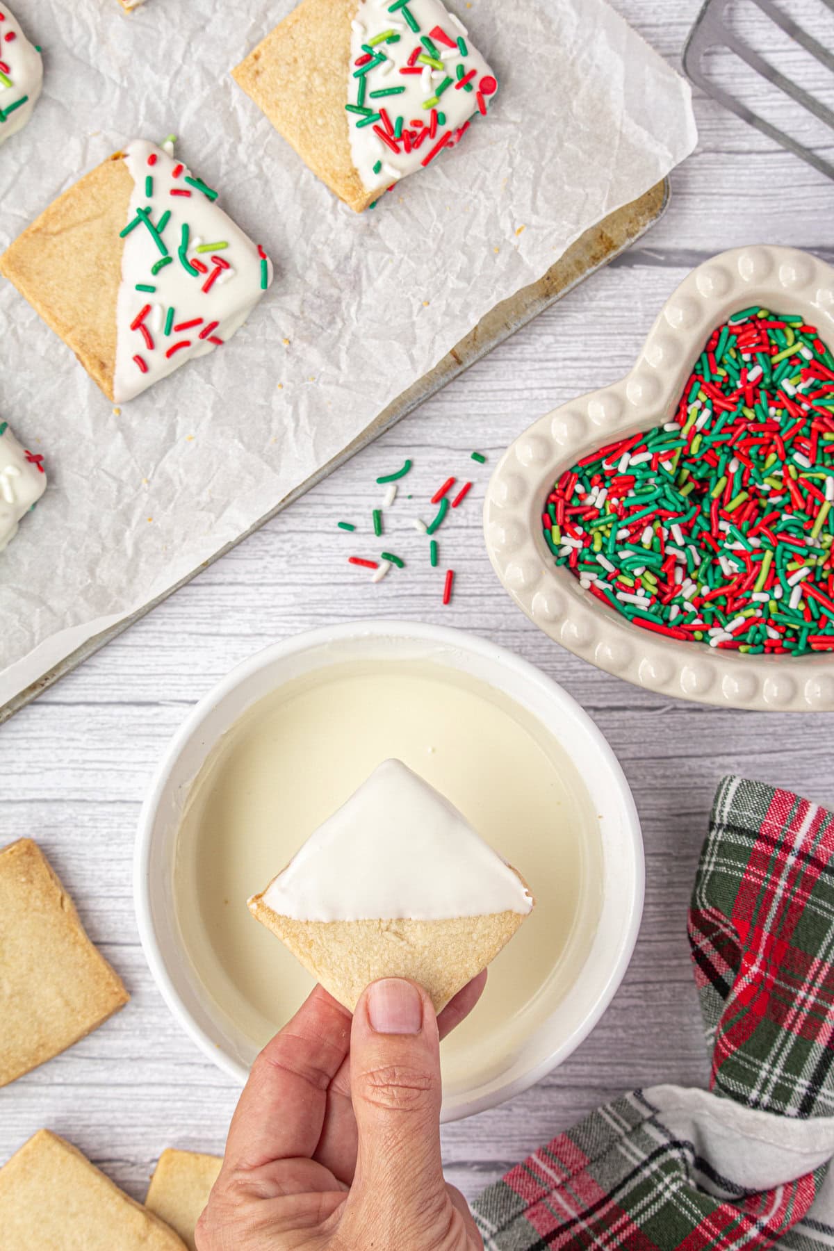 Dipping the baked shortbread cookies into melted white chocolate.