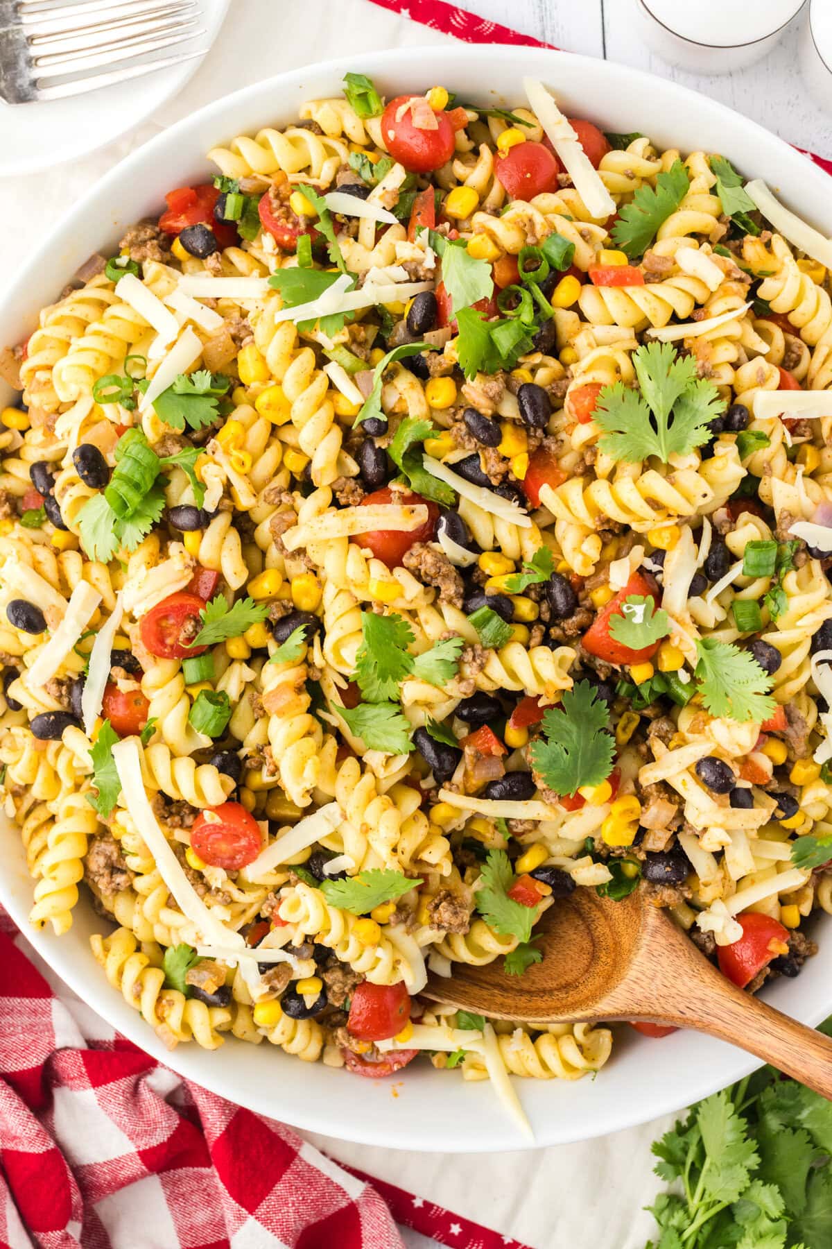 Texas pasta salad in a serving bowl with a wooden serving spoon.