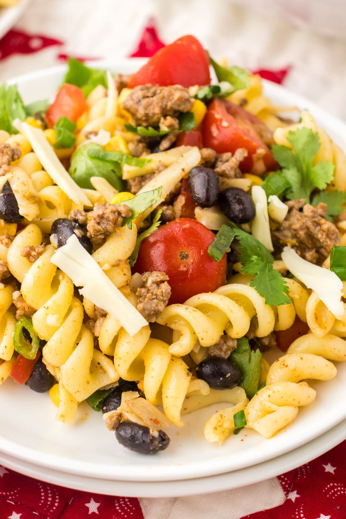 A close-up view of Texas pasta salad on a plate with cheese and cilantro.