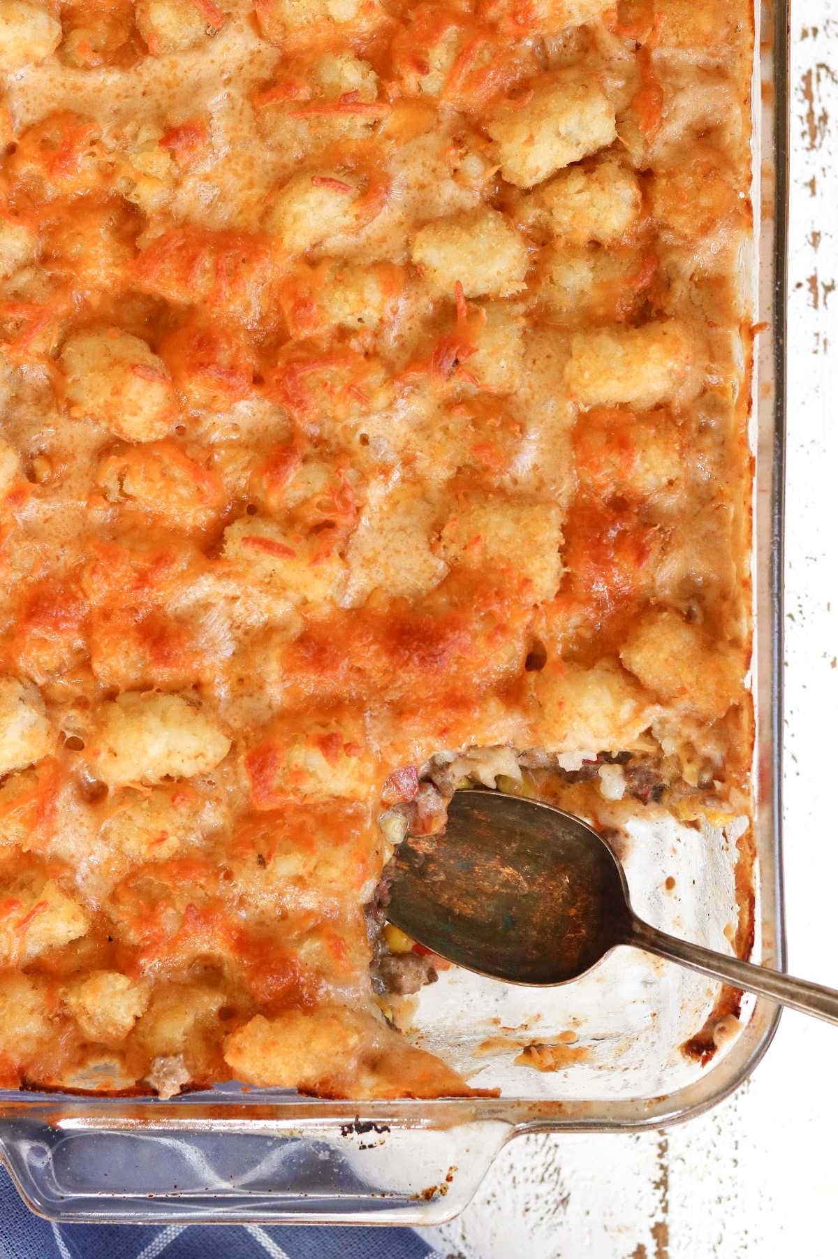 Overhead view of Cowboy Tater Tot Casserole with a serving removed showing the creamy interior of the dish.