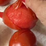 A hand peeling a tomatoe on a countertop with a title text overlay for Pinterest.