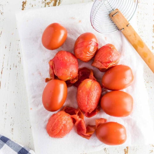 Tomatoes being peeled on a countertop.