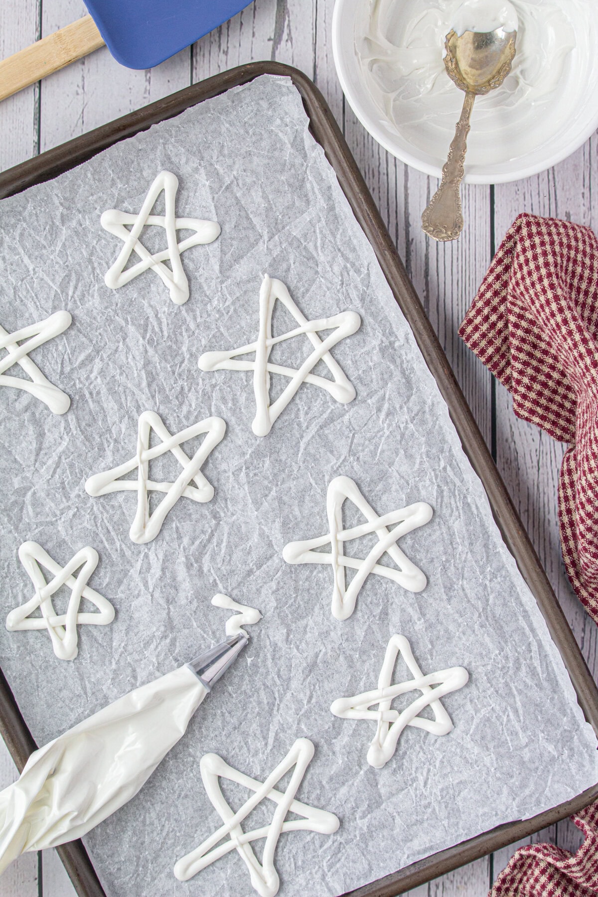 White chocolate stars being formed on a piece of parchment.