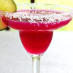 Bright pink cocktail in a margarita glass with title text overlay for Pinterest.