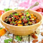 Closeup of a bowl of sweet potato salad with a serving spoon in it.