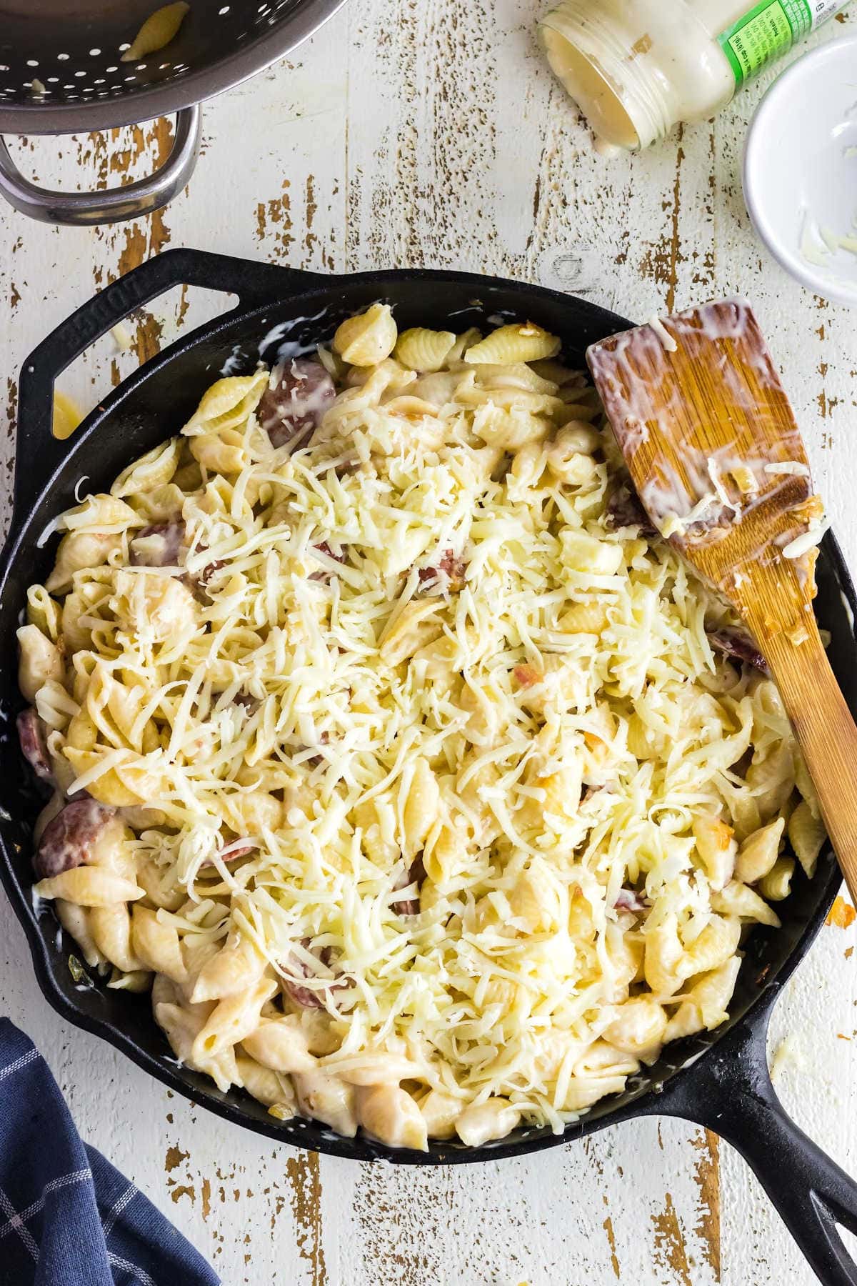 Cheese has been sprinkled on top of the pasta and sausage in the pan.