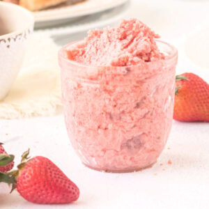 A jar of strawberry butter on a table.