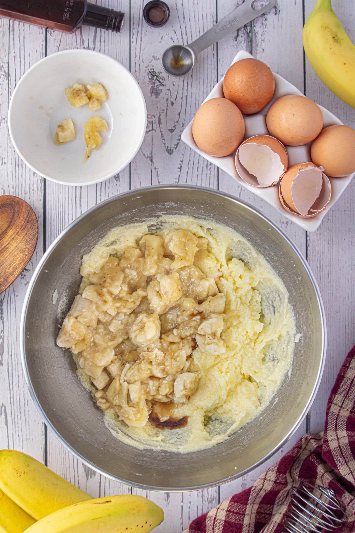 Bananas are added to the butter, sugar, and egg mixture in the mixing bowl.