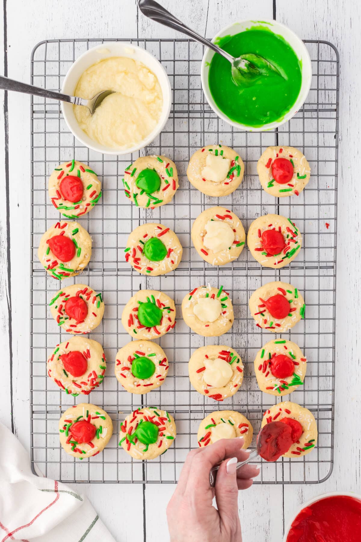 Spooning the filling into the center of each thumbprint cookie.