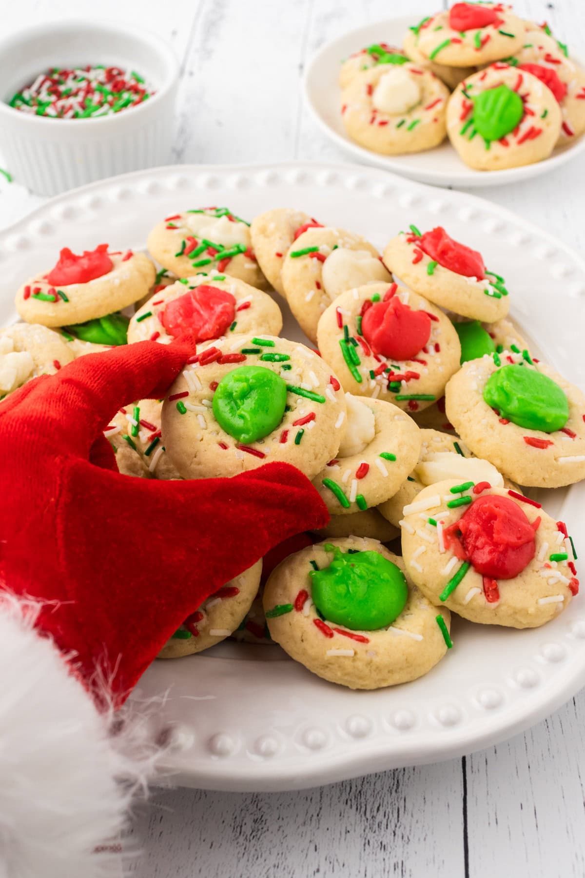 Santa's hand reaching for a platter of Christmas thumbprint cookies.