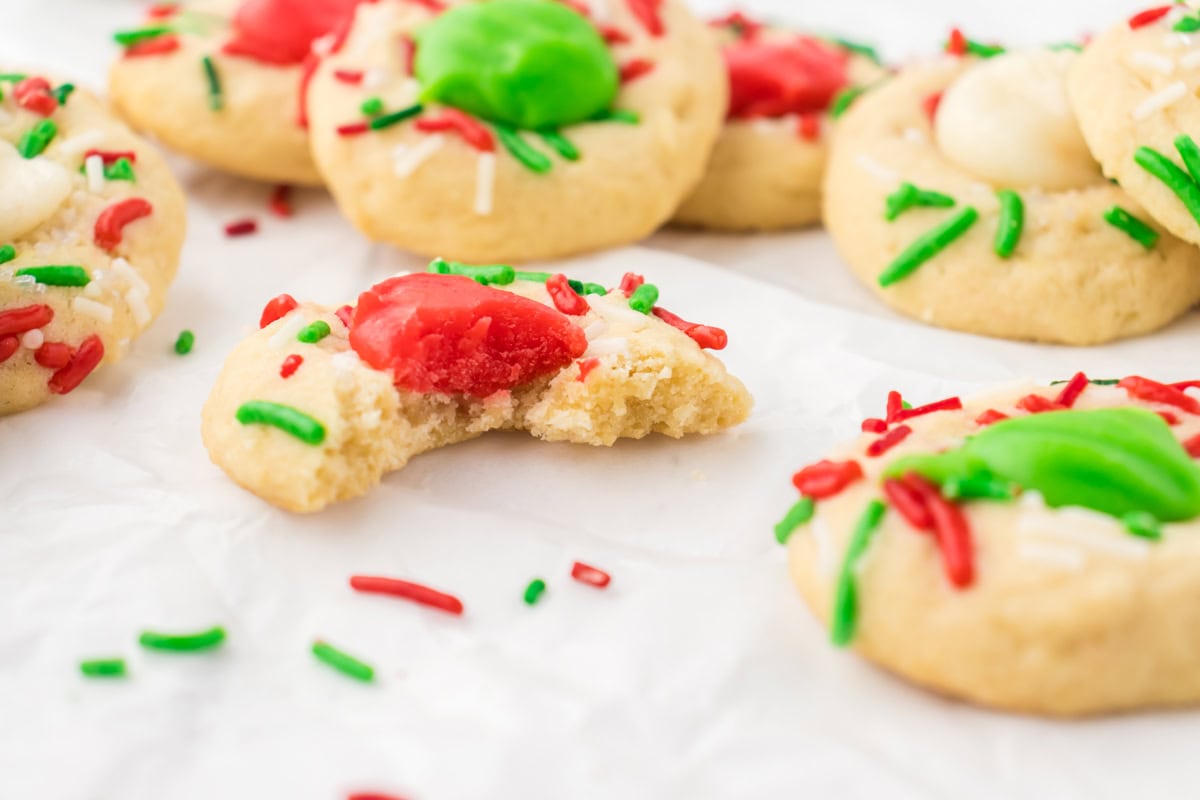 A close-up photo of a thumbprint cookie with a bite taken out of it.