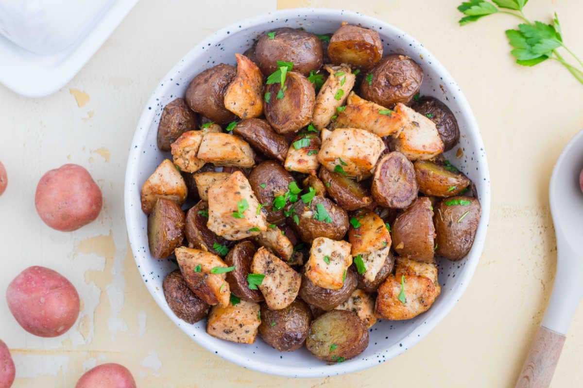 Garlic butter chicken and potatoes in a serving bowl with parsley.