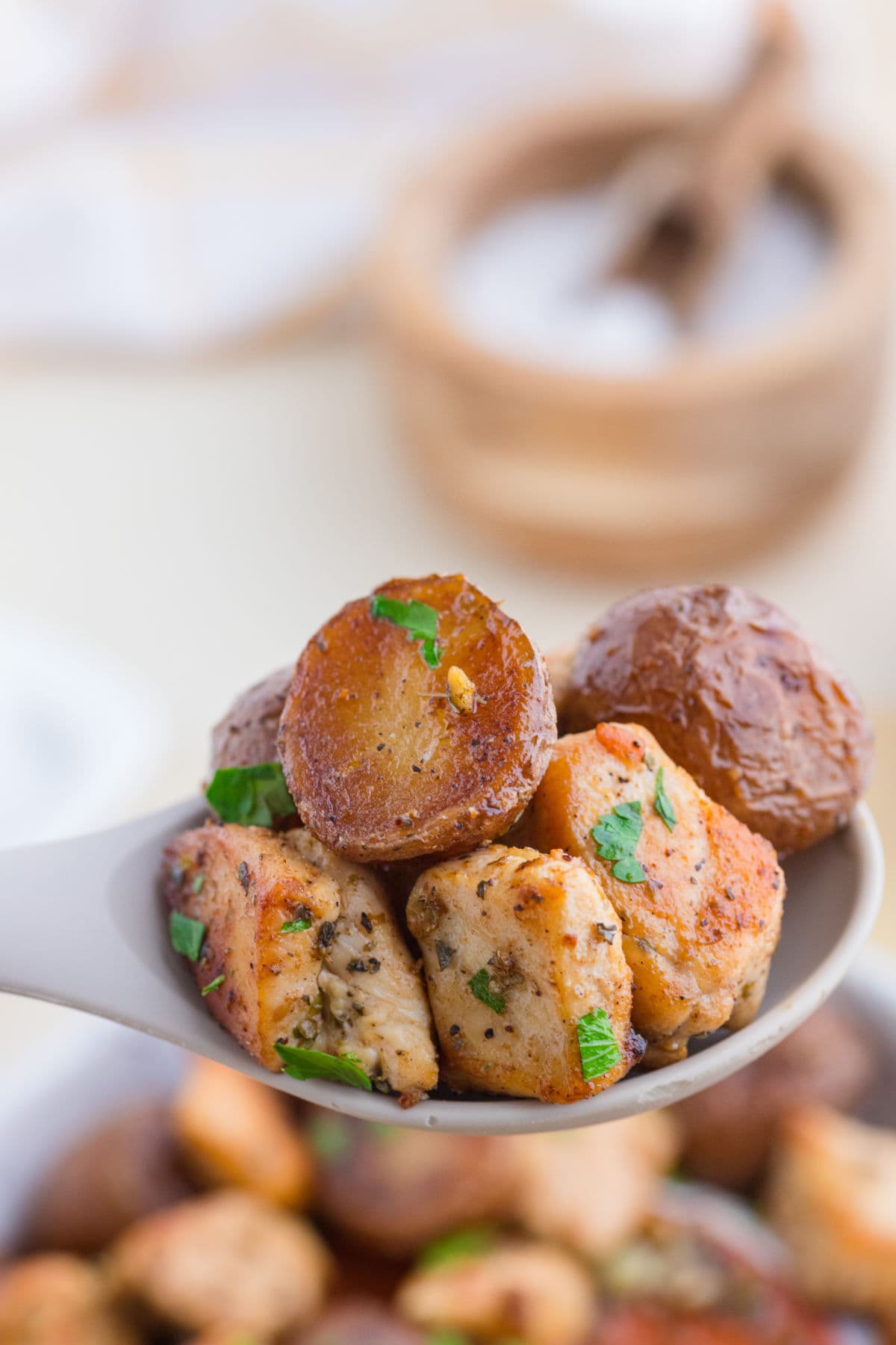 A close-up view of garlic butter chicken and potatoes on a serving spoon.