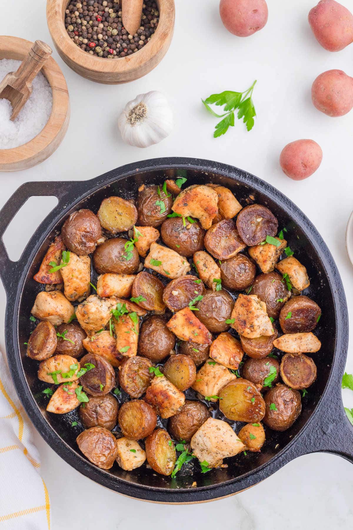 Overhead view of garlic butter chicken and potatoes in a skillet.