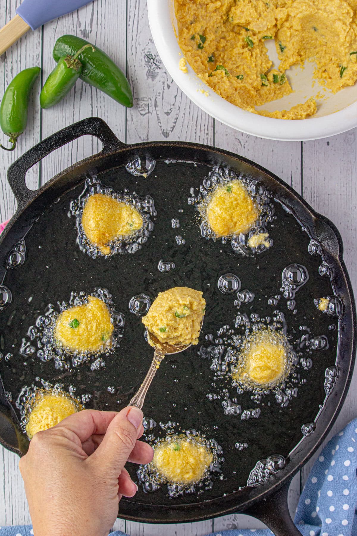 Adding the hushpuppy batter to the oil in a skillet.