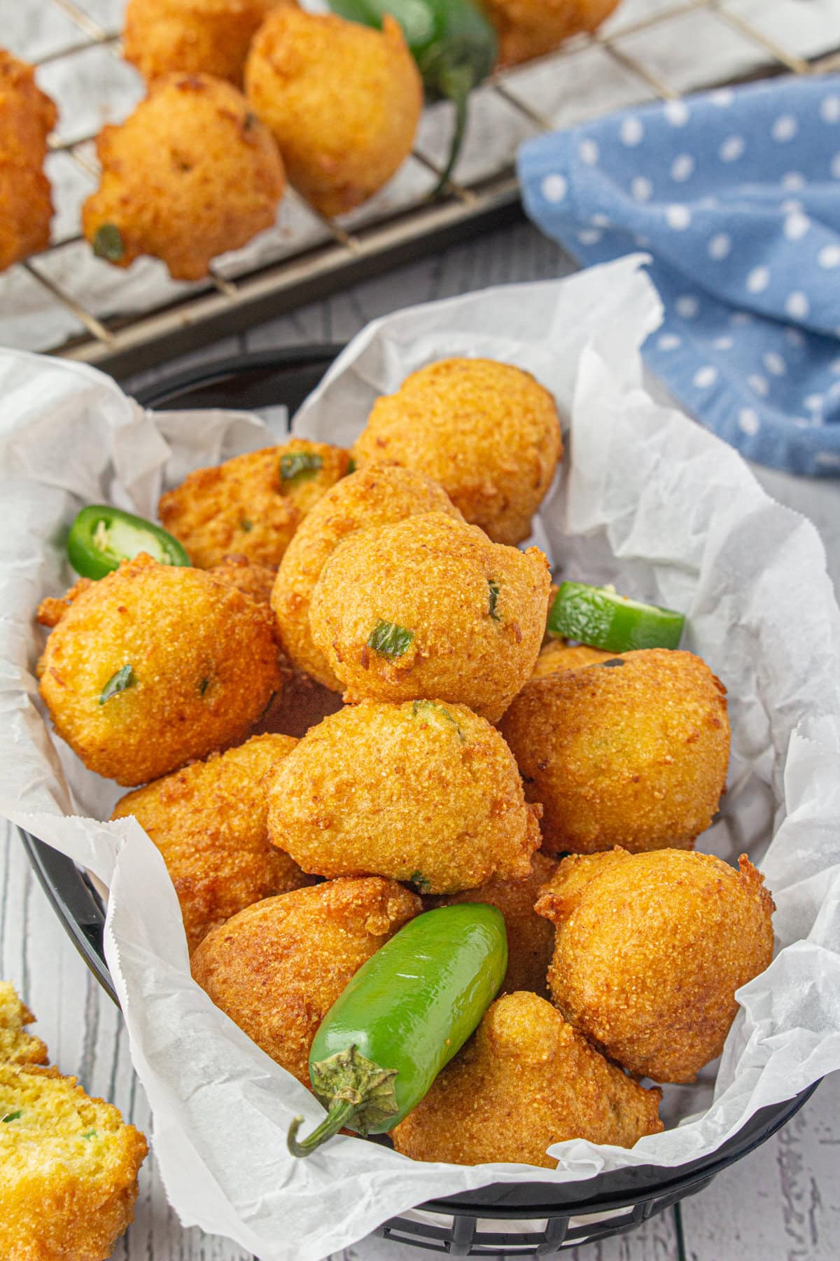 Southern hushpuppies in a basket with jalapeno slices for garnish.