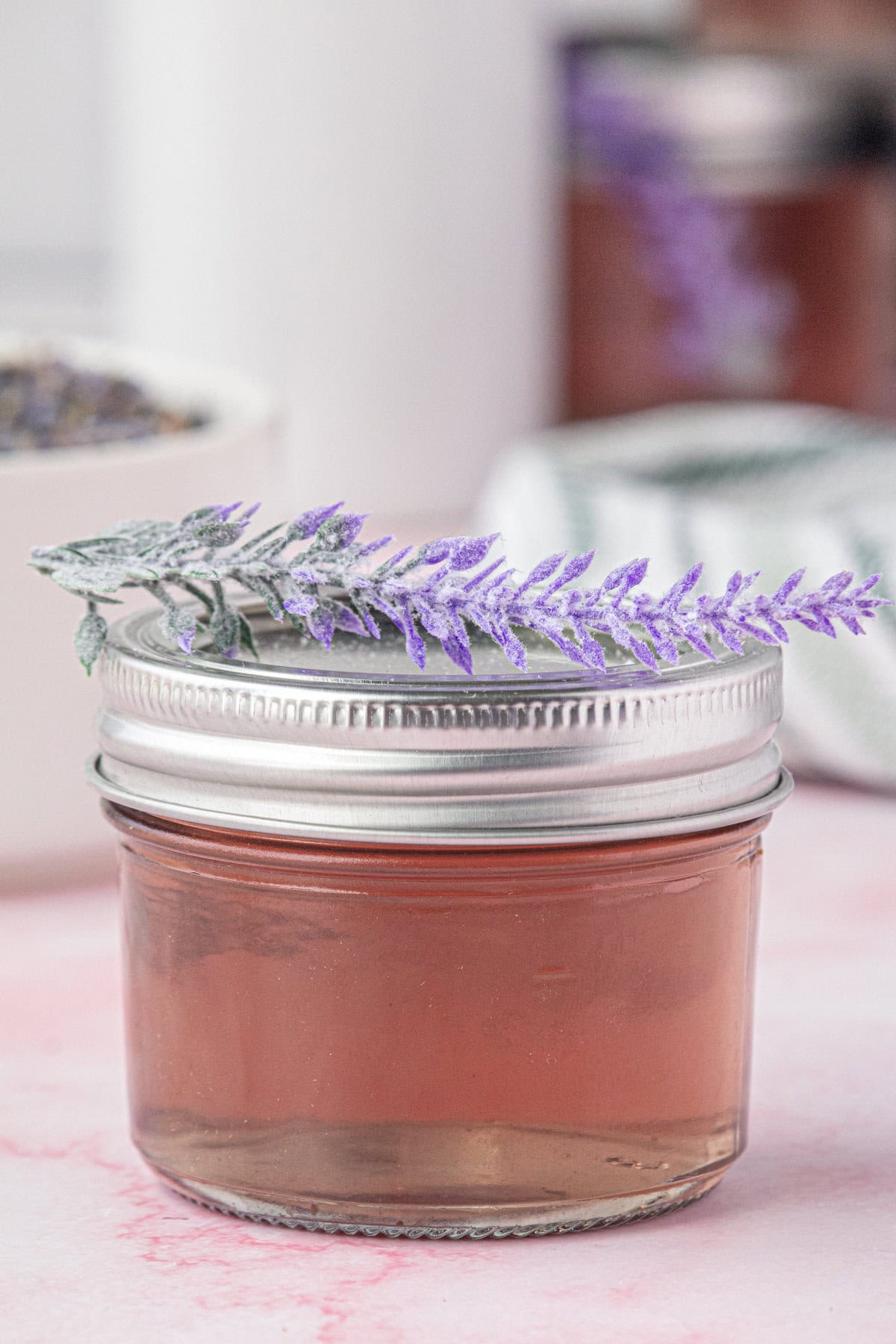 A mason jar with lavender simple syrup and a sprig of lavender on top of the lid.